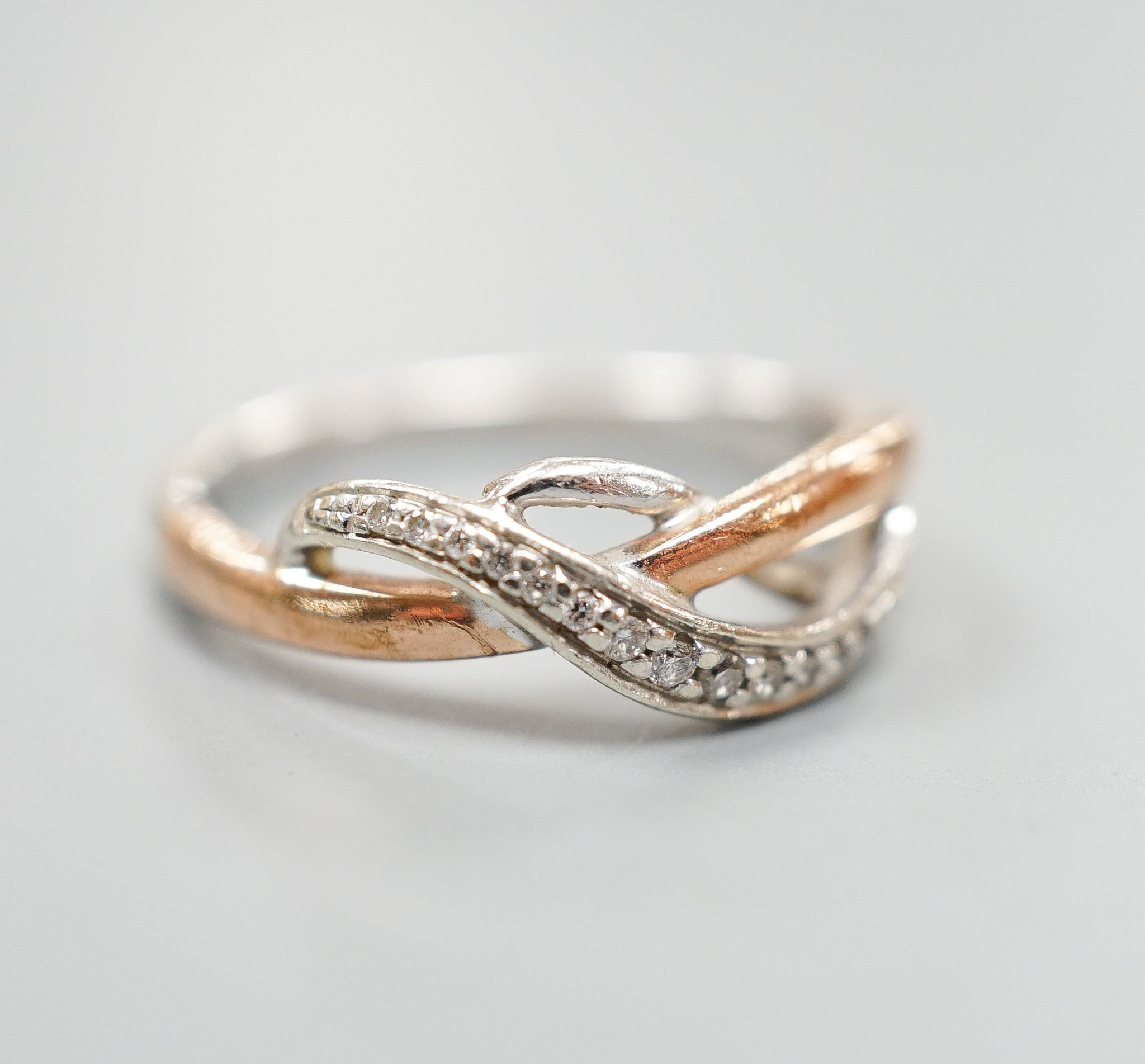 A modern two colour 9ct gold and diamond chip set crossover ring, size Q, gross weight 3.8 grams.